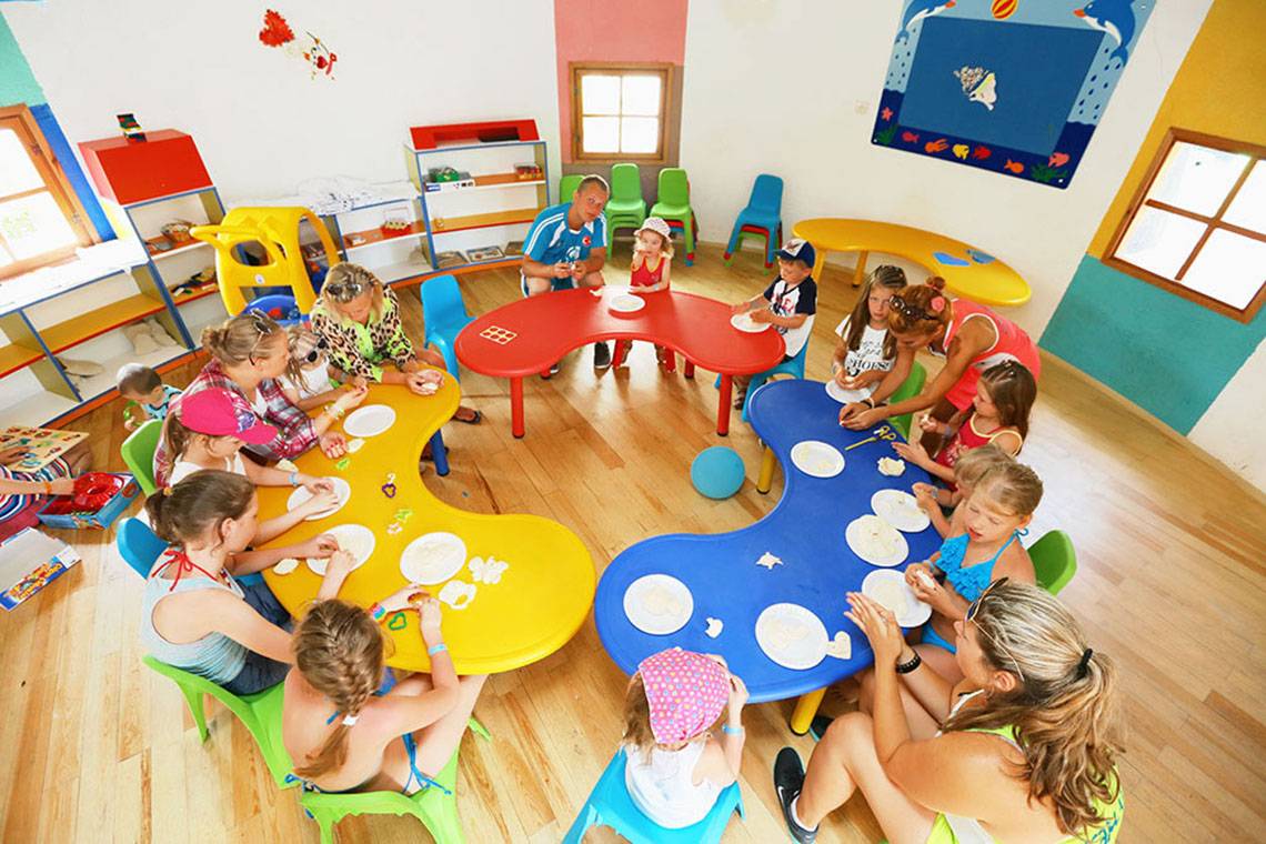 Kindergruppe im Spielzimmer des Selectum Family Comfort Side Hotel, alle sitzen an Tischen und spielen