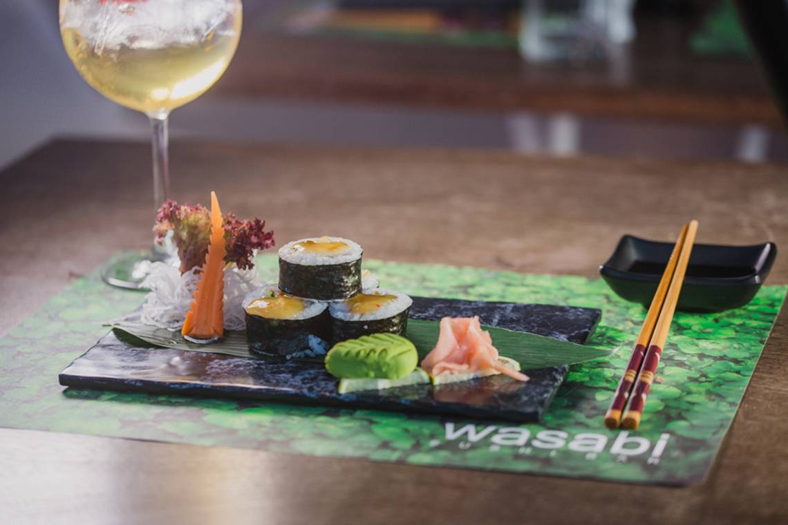 Ein Teller mit Sushi und einem Glas Getränk auf einem Tisch im Napa Plaza Hotel.