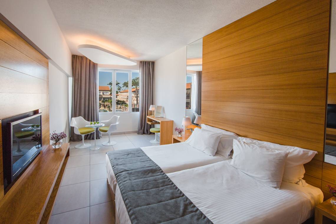 Innenansicht eines Doppelzimmers im Napa Plaza Hotel mit zwei Betten, einem Fernseher und einem Schreibtisch.
