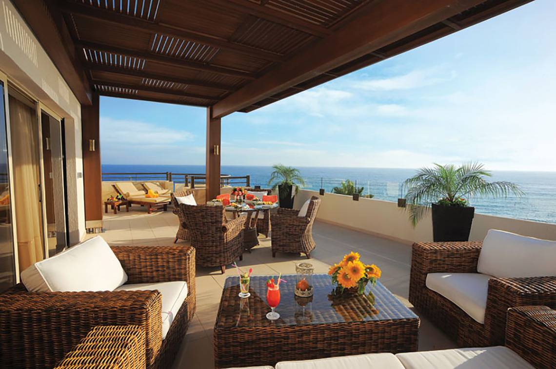 Terrasse des Alexander The Great Hotels mit Blick auf das Meer und Korbmöbeln.