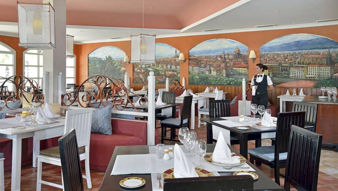 Innenansicht des Paradisus Princesa del Mar Restaurants mit einer Kellnerin, die eine Tischplatte bedient.