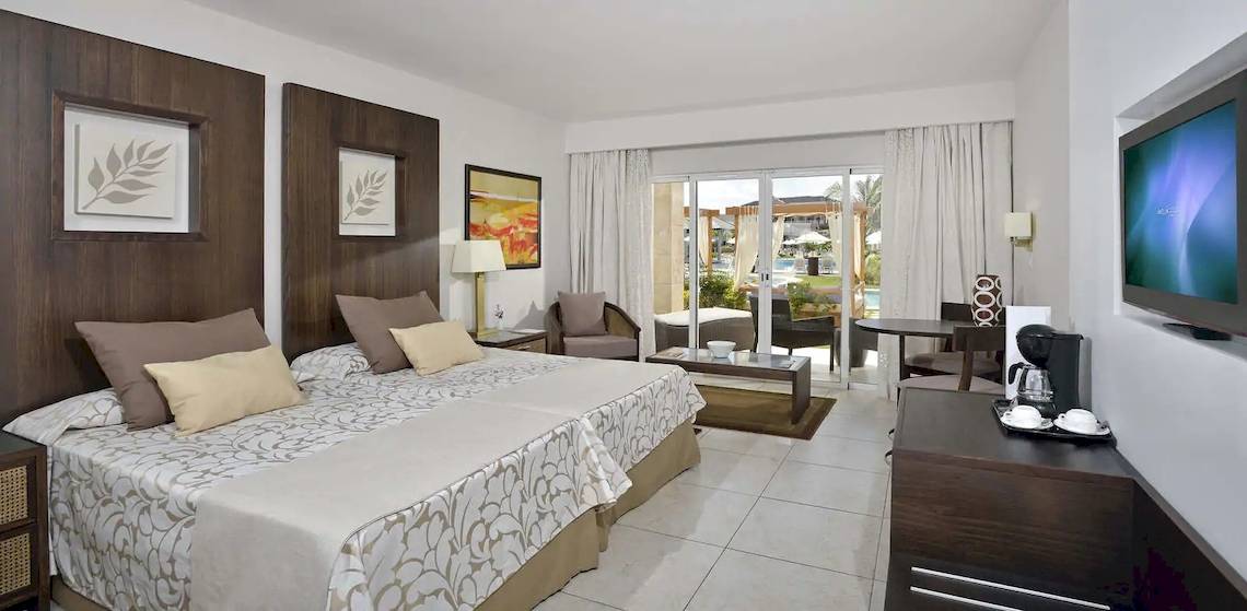 Hotelzimmer im Paradisus Princesa del Mar Resort & Spa mit Doppelbett, Wohnzimmerbereich und Terrassentür.