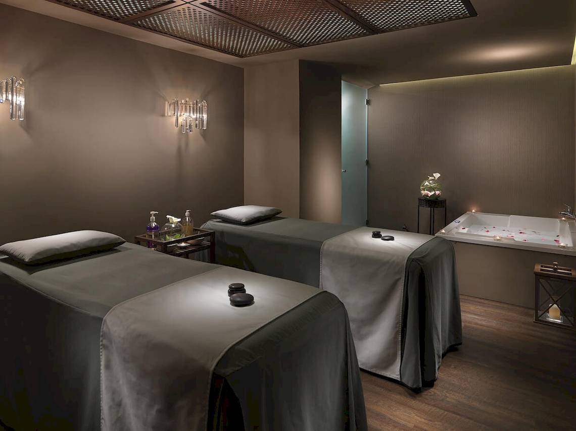 Spa-Behandlungsraum im H10 Conquistador Hotel mit zwei Massageliegen und einer Badewanne.