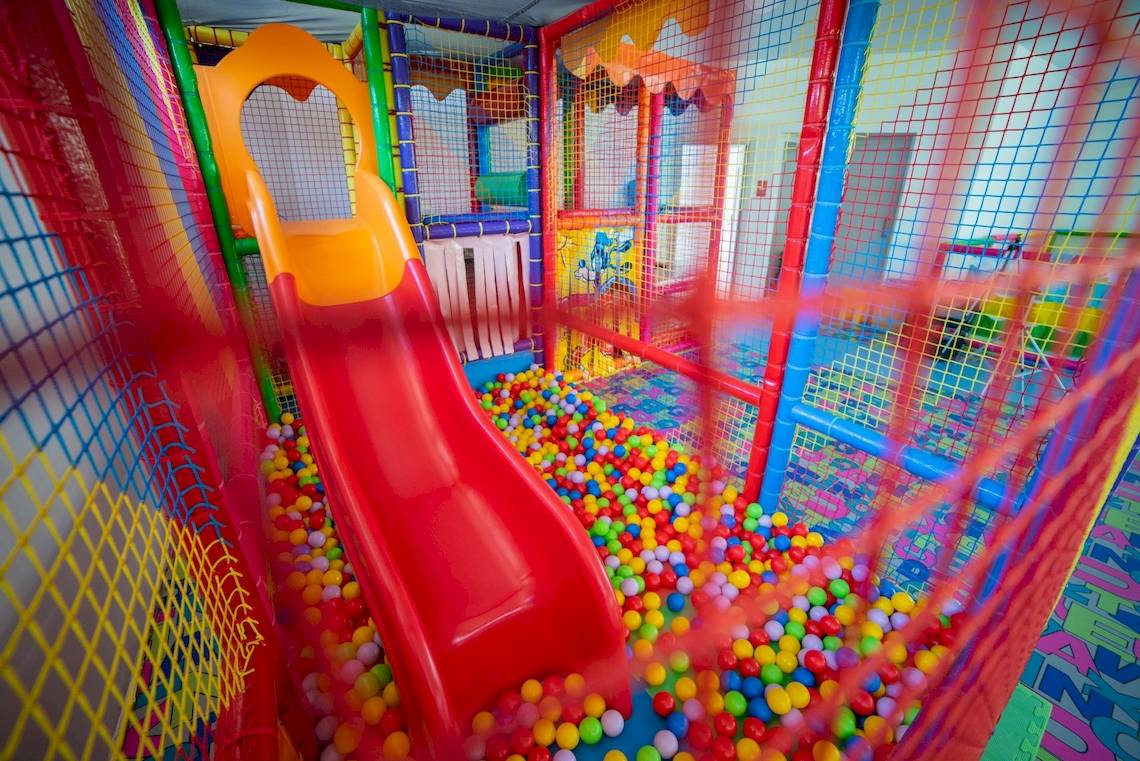 Kinderspielplatz im Ramla Bay Resort mit einer roten Rutsche und bunten Bällen.