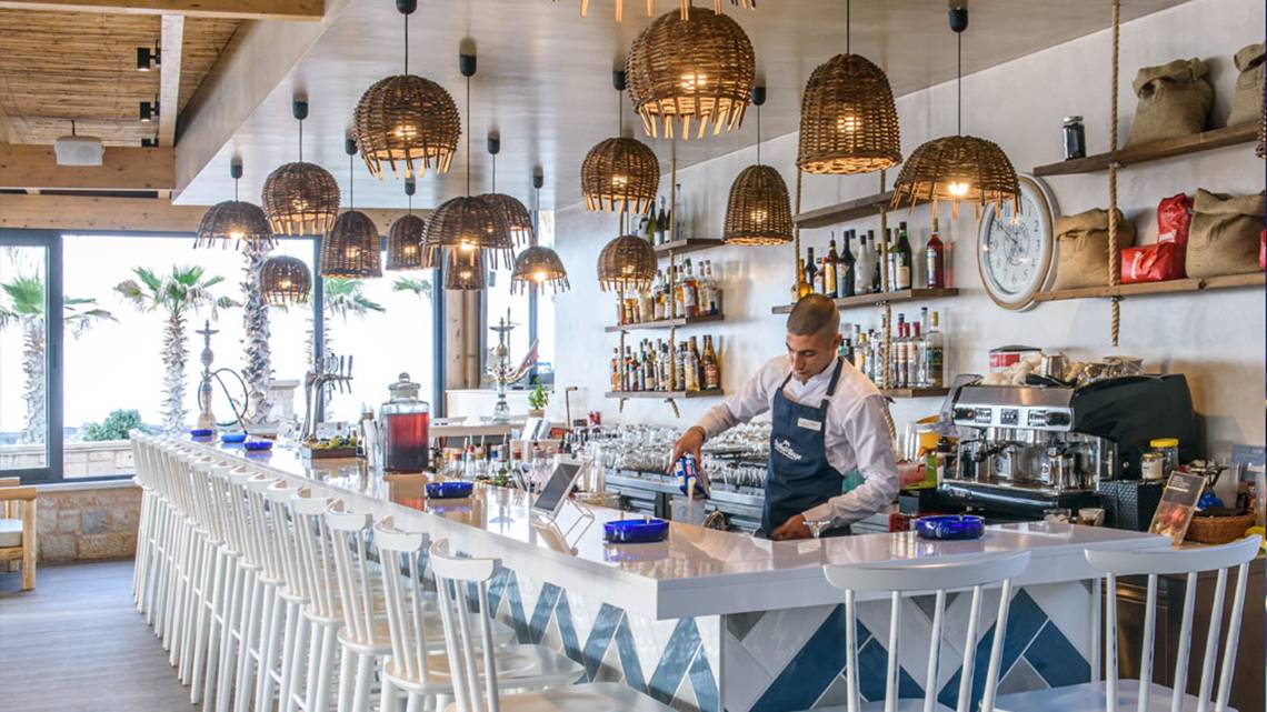 Ein Barkeeper serviert Getränke in der Bar des Stella Palace Resort & Spa.