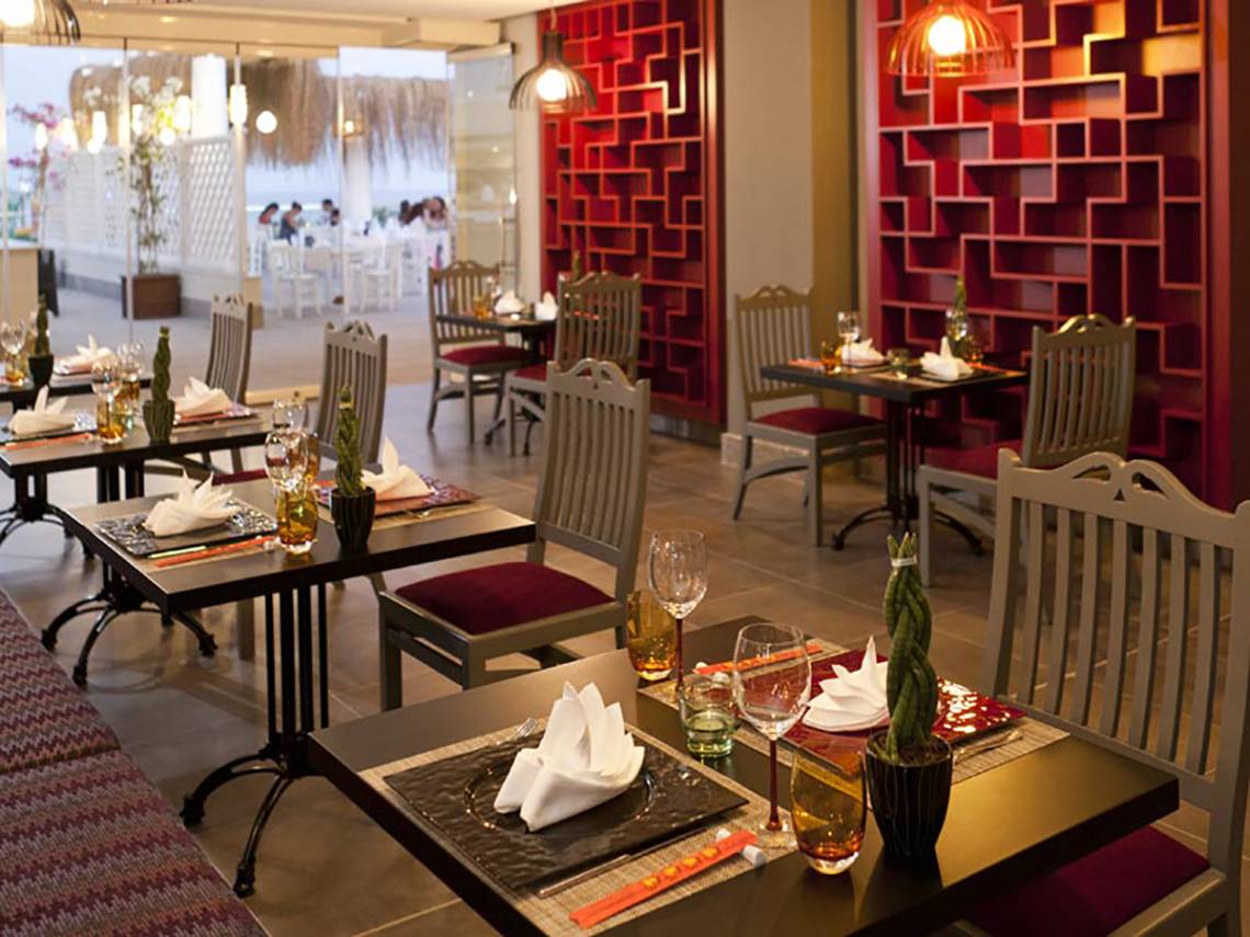 Innenansicht des Restaurants im Paloma Oceana Hotel mit roten Wänden und gedeckten Tischen.