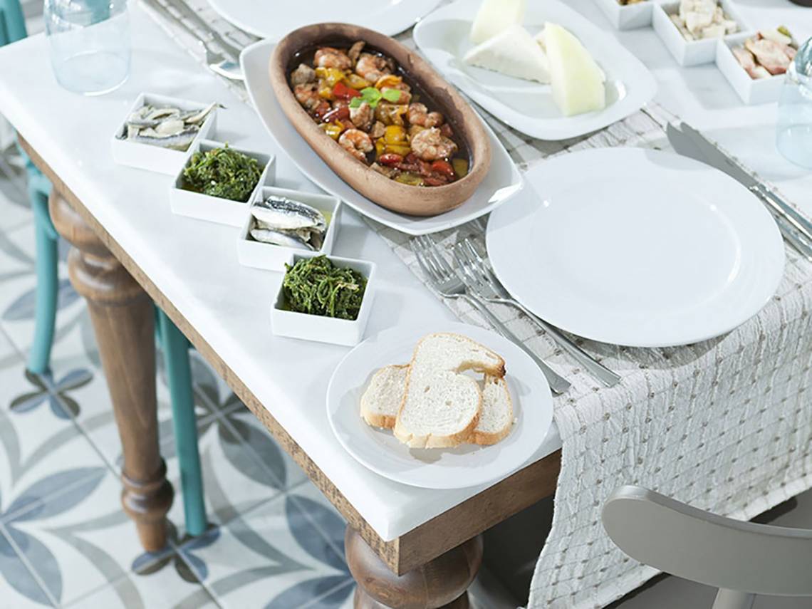 Tisch mit verschiedenen Speisen im Paloma Oceana Hotel, darunter gebratene Garnelen, Käse, Oliven und Brot.
