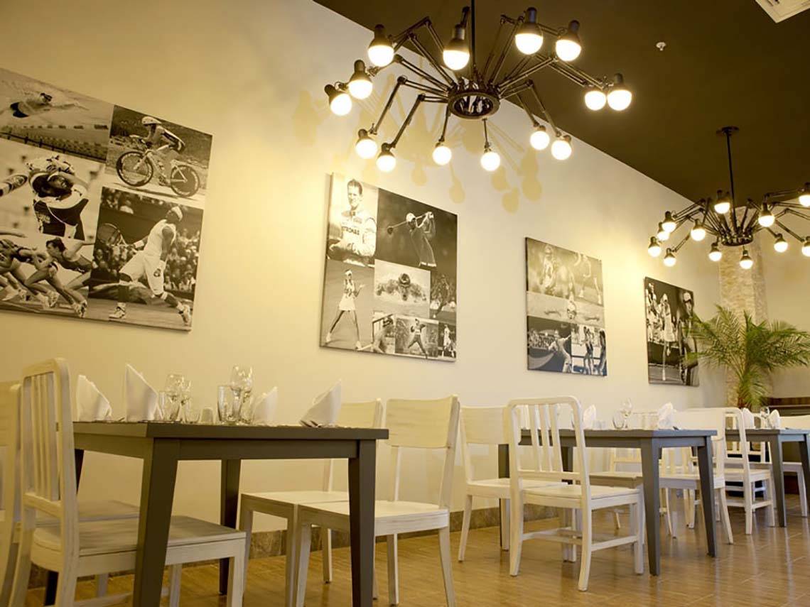 Innenansicht des Restaurants im Paloma Oceana Hotel mit weißen Tischen und Stühlen, Wandkunst und Kronleuchtern.