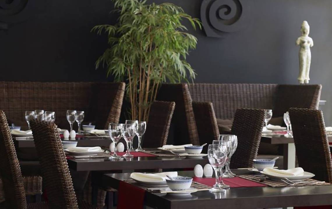 Innenansicht des Restaurants im Porto Bello Royal Hotel mit gedeckten Tischen und einer Statue.