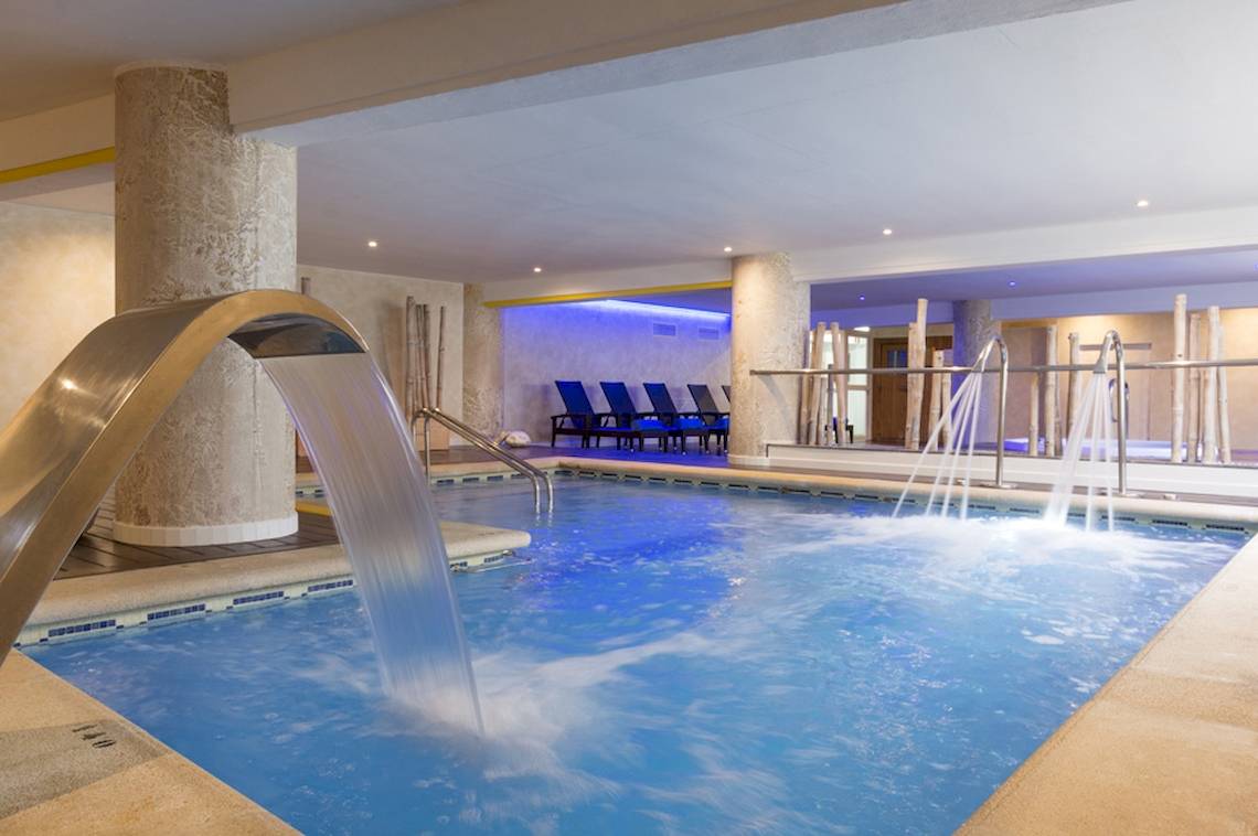 Innenpool des HSM Golden Playa Hotels mit Wasserfall und blauen Liegestühlen