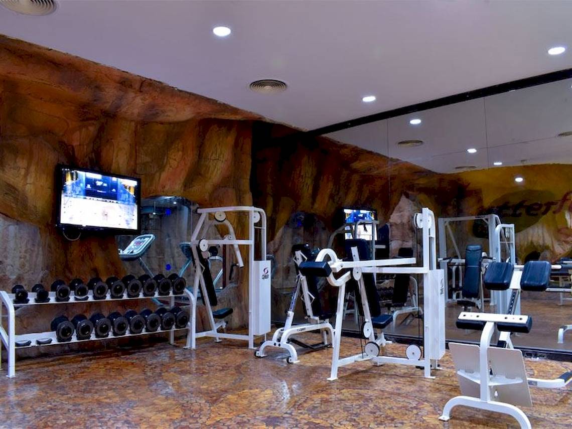 Fitnesscenter im Parrotel Beach Resort mit verschiedenen Geräten und einer steinernen Wand.
