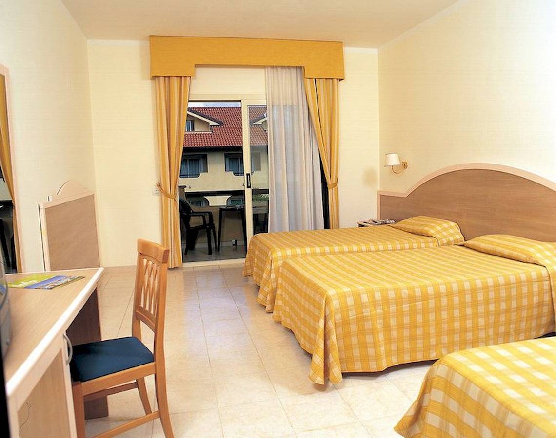 Doppelzimmer mit Balkon im Falkensteiner Club Funimation Garden Calabria, mit zwei Betten und einem Schreibtisch.