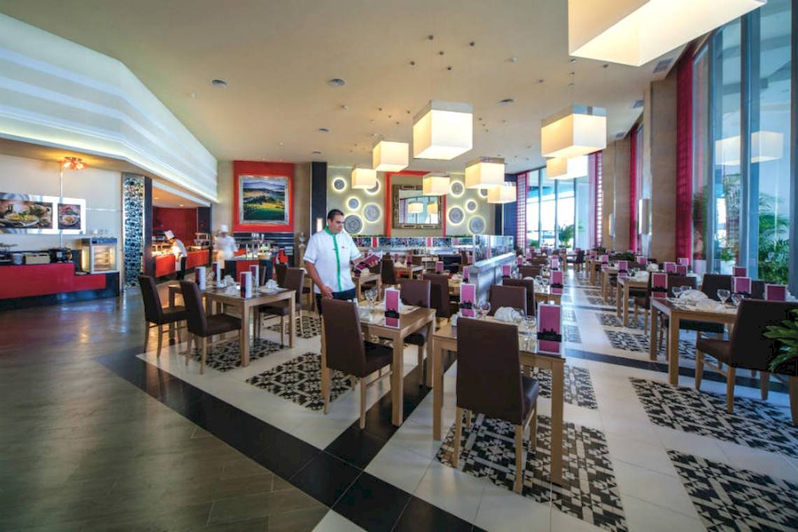 Innenansicht des Riu Cancun Hotel Restaurants mit einem Kellner, der die Tische vorbereitet.