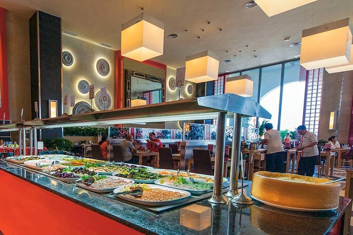 Buffetbereich im Riu Cancun Hotel mit verschiedenen Gerichten und Gästen.