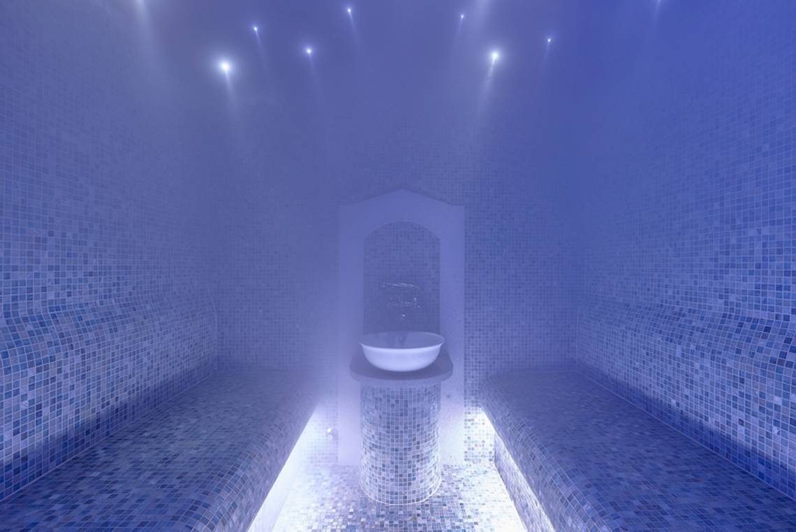 Ein Dampfbad im Astir Beach Hotel auf Kreta mit blauen Fliesen und einer weißen Schüssel.