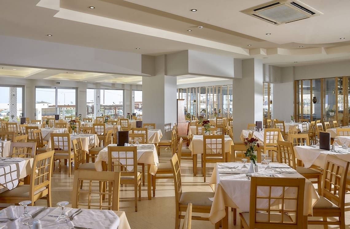 Restaurant im Astir Beach Hotel auf Kreta mit vielen gedeckten Tischen und Stühlen.
