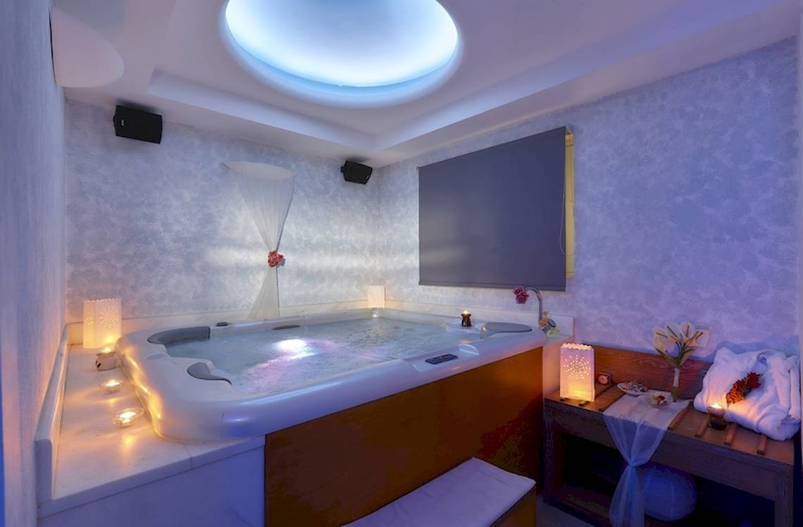 Whirlpool im Schlafzimmer des Astir Beach Hotels auf Kreta mit beleuchteten Kerzen und weichen Handtüchern.