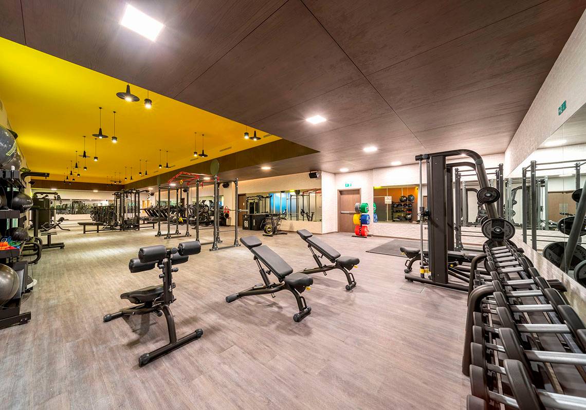 Fitnesscenter im FIVE Jumeirah Village Hotel mit verschiedenen Trainingsgeräten und einer gelben Decke.