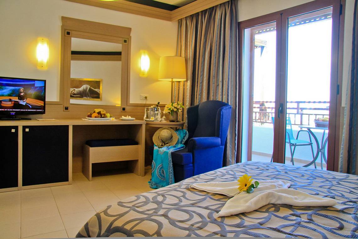 Ein luxuriöses Hotelzimmer mit einem Bett, einem Schreibtisch, einem Fernseher und einem Balkon.