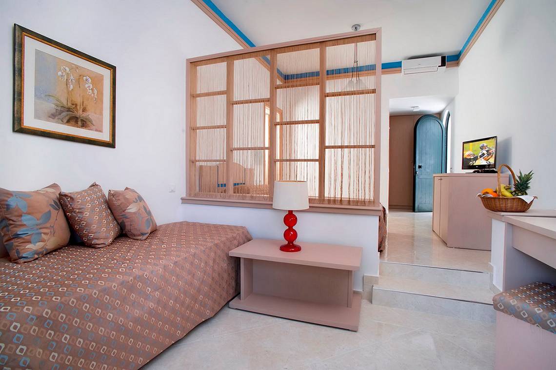 Innenansicht eines Zimmers im Nana Golden Beach Hotel mit einem Bett, einem Tisch und einer Lampe.