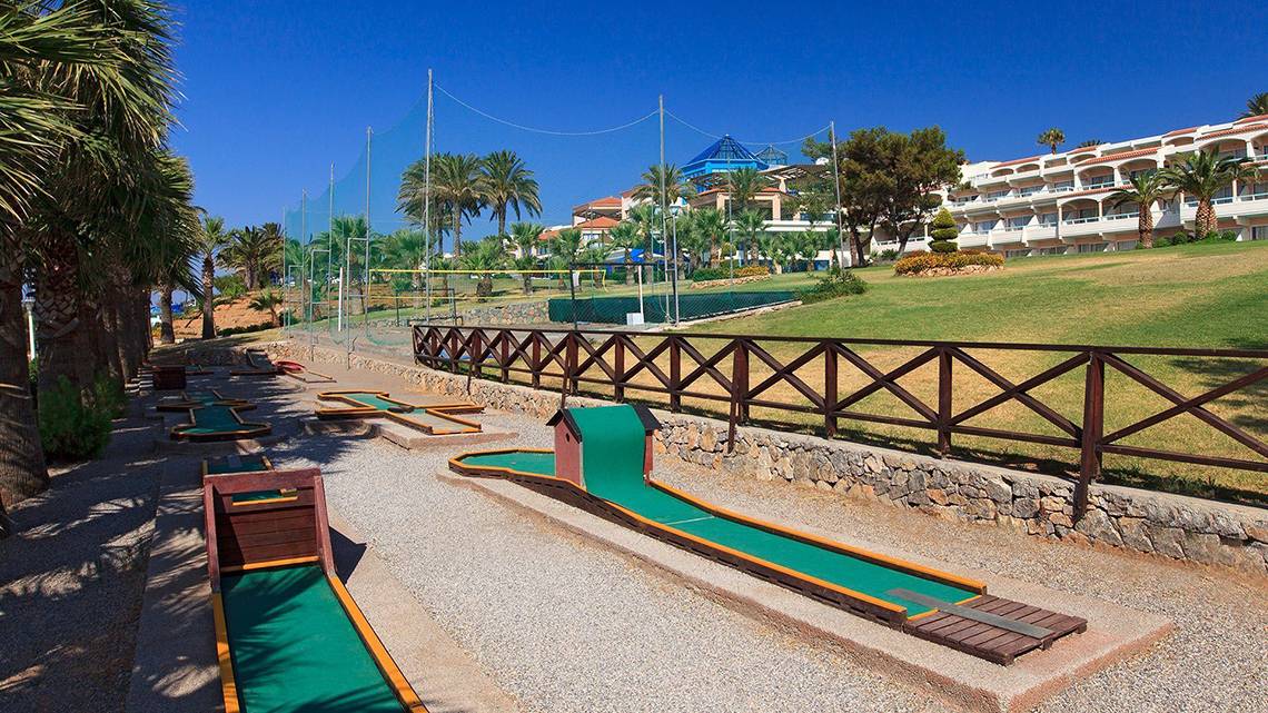 Minigolfplatz im Freien im Rodos Princess Beach Hotel mit Palmen und Gebäude im Hintergrund.