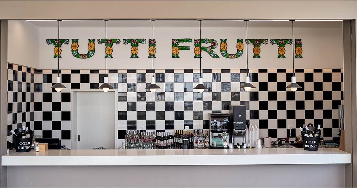 Bar im Hotel Esperides Beach Resort mit schwarz-weißem Schachbrettmuster und 'Tutti Frutti' Schriftzug.