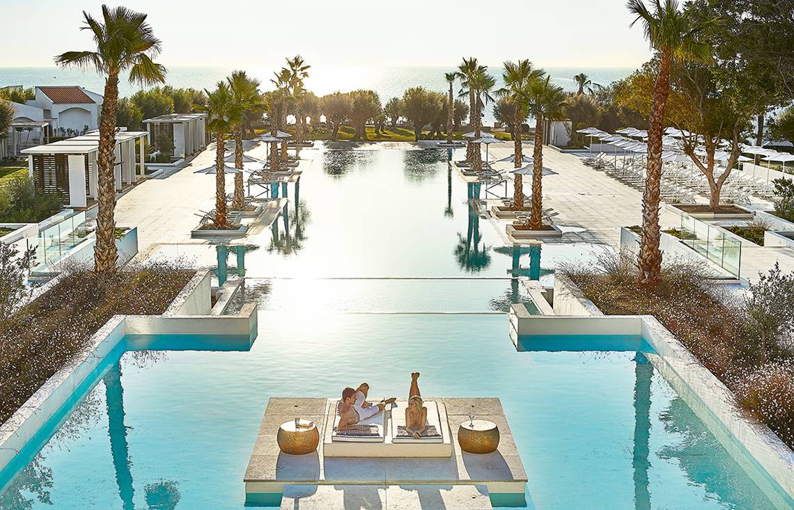 Poolbereich des Grecotel Lux Me Dama Dama Hotels mit Paar, das sich entspannt.
