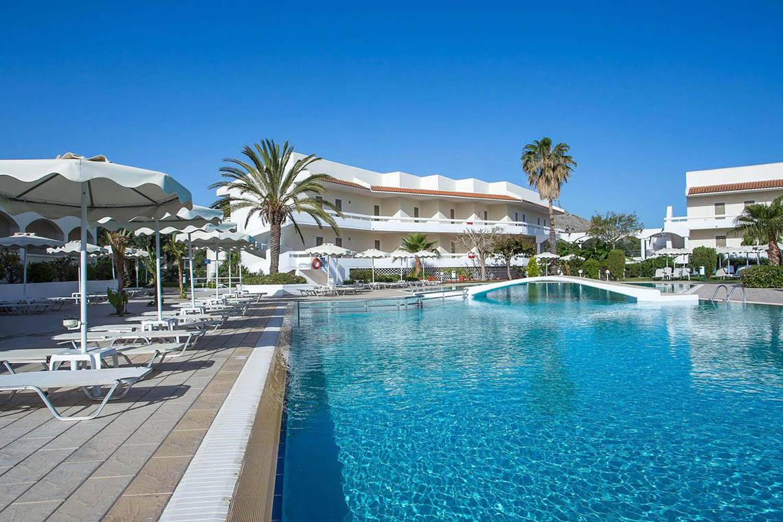 Außenpool des Niriides Beach Hotels mit weißen Liegestühlen und Sonnenschirmen.