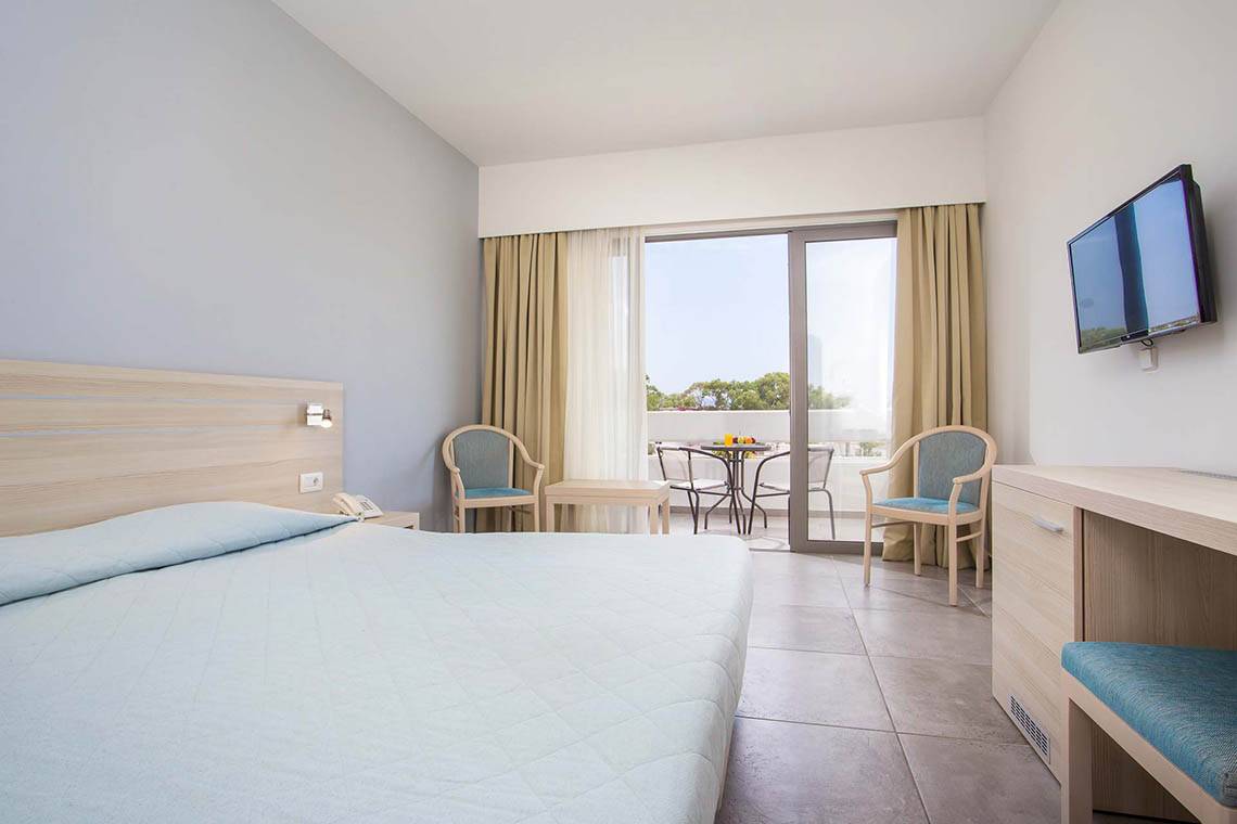 Zimmer im Niriides Beach Hotel mit Bett, Schreibtisch und Balkon