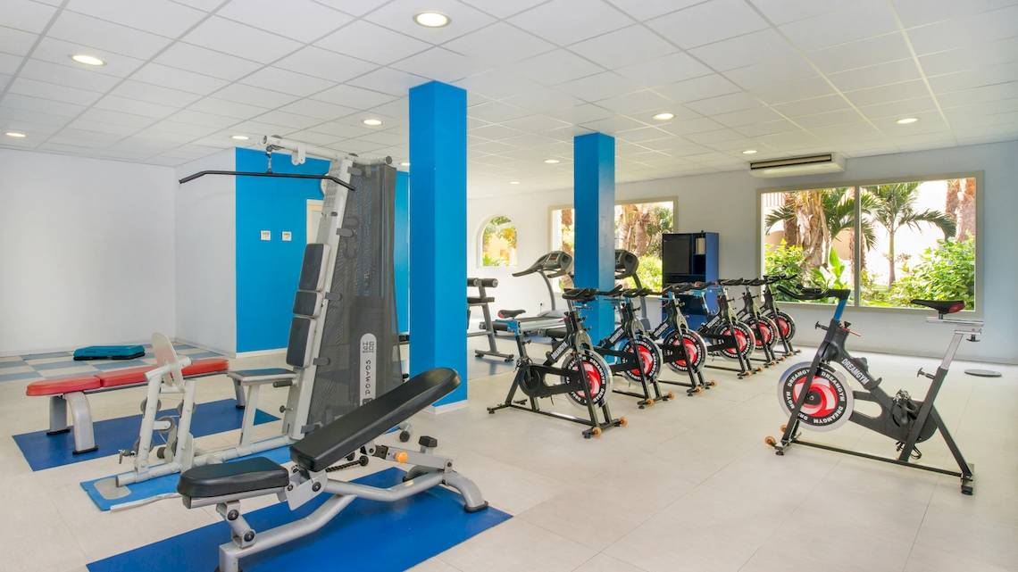 Fitnessstudio im VOI Praia De Chaves Resort mit verschiedenen Geräten auf blauen Matten.