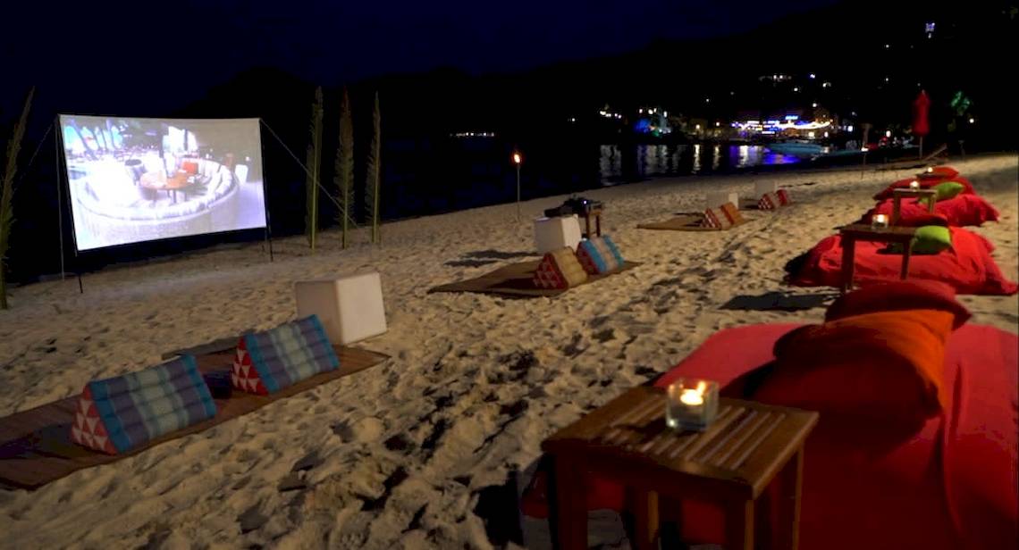 Strandkino-Nachtveranstaltung im Anantara Rasananda Koh Phangan Villas mit Leinwand und roten Kissen.