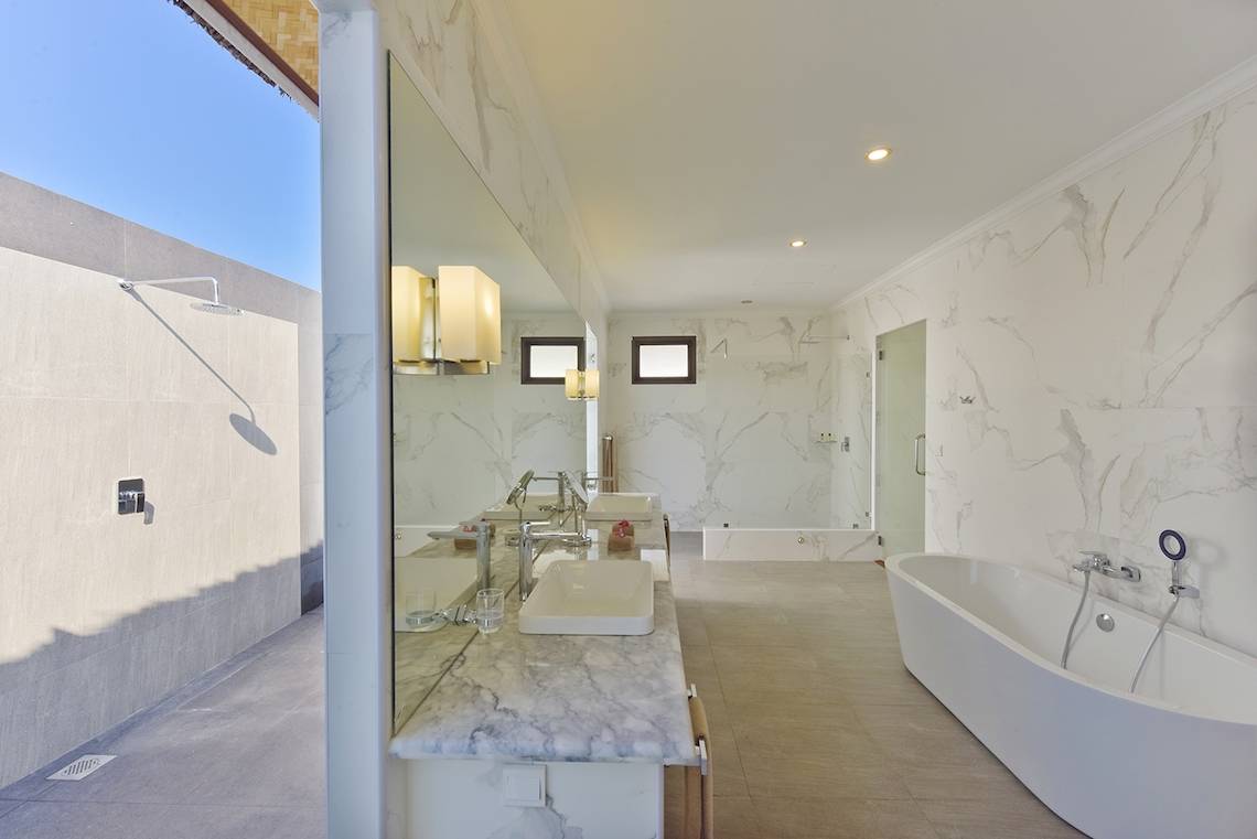 Ein Badezimmer mit Doppelwaschbecken, Spiegel und Badewanne in einer luxuriösen Einrichtung.