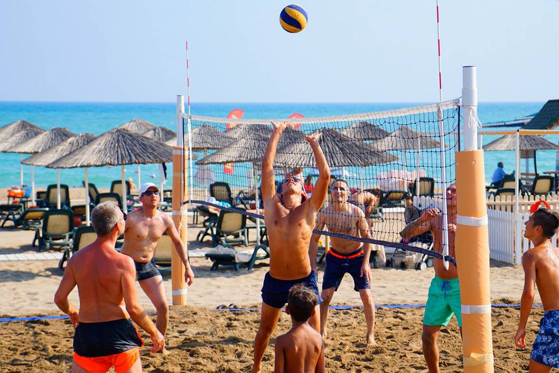 Ein Volleyballspiel am Strand im Baia Lara Hotel mit mehreren Spielern und einem Ball in der Luft.
