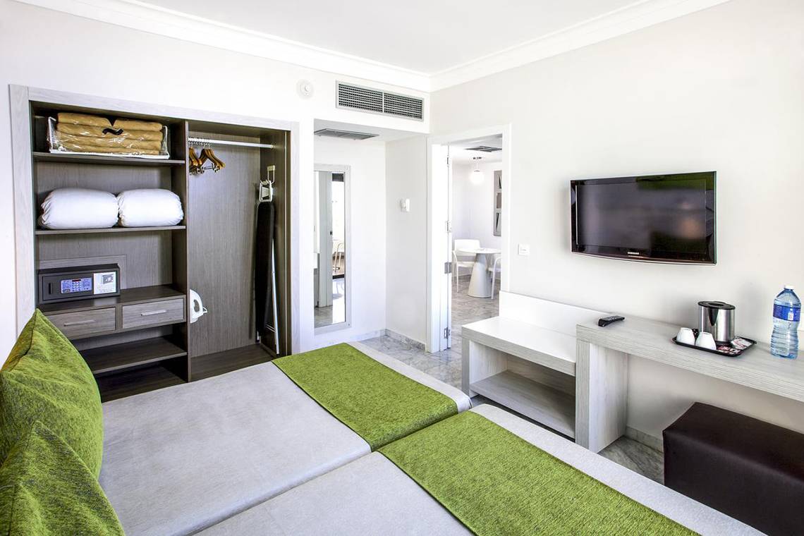Doppelzimmer im Sol Palmeras Hotel mit zwei Betten, Fernseher, Kleiderschrank und Nachttisch.