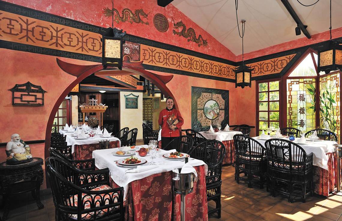 Innenansicht des Sol Palmeras Restaurants mit asiatischem Dekor und einem Mitarbeiter, der die Tische bedient.