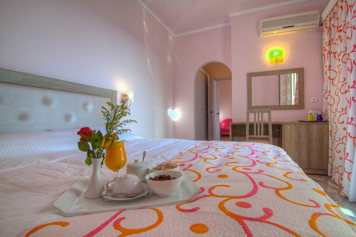 Fruehstuecksplatte auf einem Bett im Solimar Dias Hotelzimmer mit buntem Bettlaken und Vasen.