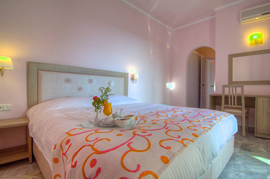 Schlafzimmer mit Frühstücksplatte im Solimar Dias Hotel, mit rosa Wänden und blumigem Bettwäsche.