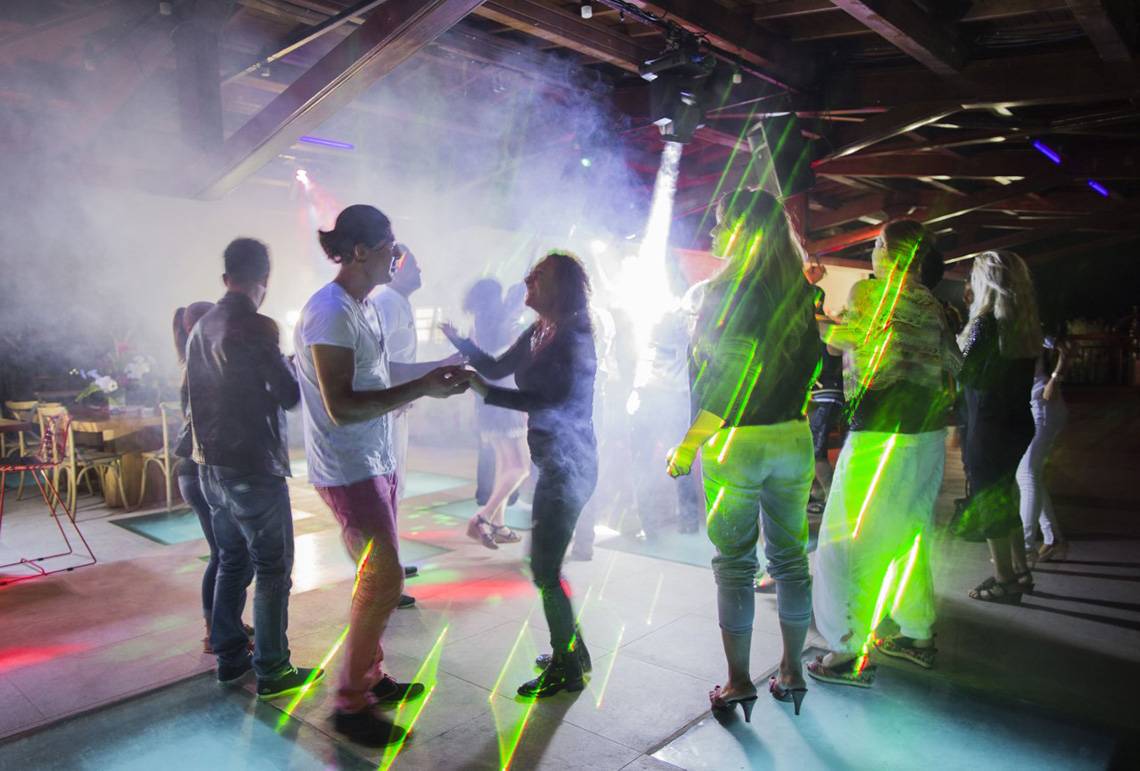 Mehrere Leute tanzen in einer Disco mit Lichteffekten und Rauch.
