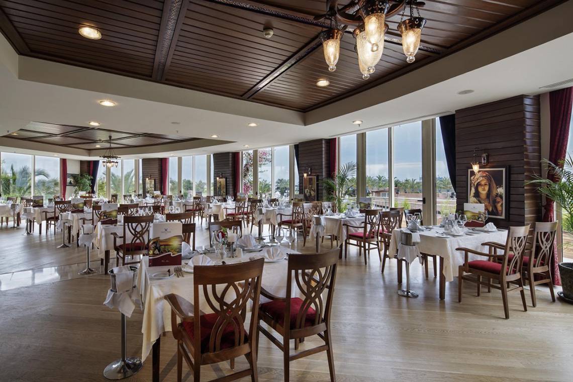 Innenansicht des Restaurants im Liberty Hotels Lara mit gedeckten Tischen und Stühlen.