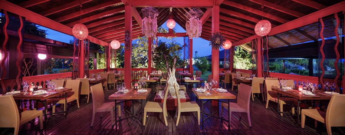 Innenansicht des Restaurants im Liberty Hotels Lara mit roten Säulen und Holzboden.