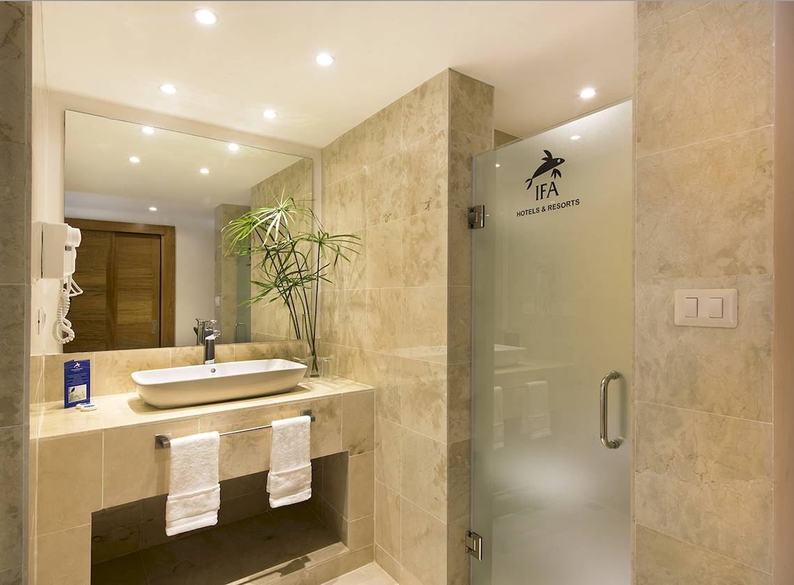 Badezimmer im IFA Villas Bavaro Hotel mit Waschbecken, Spiegel und Glastür.