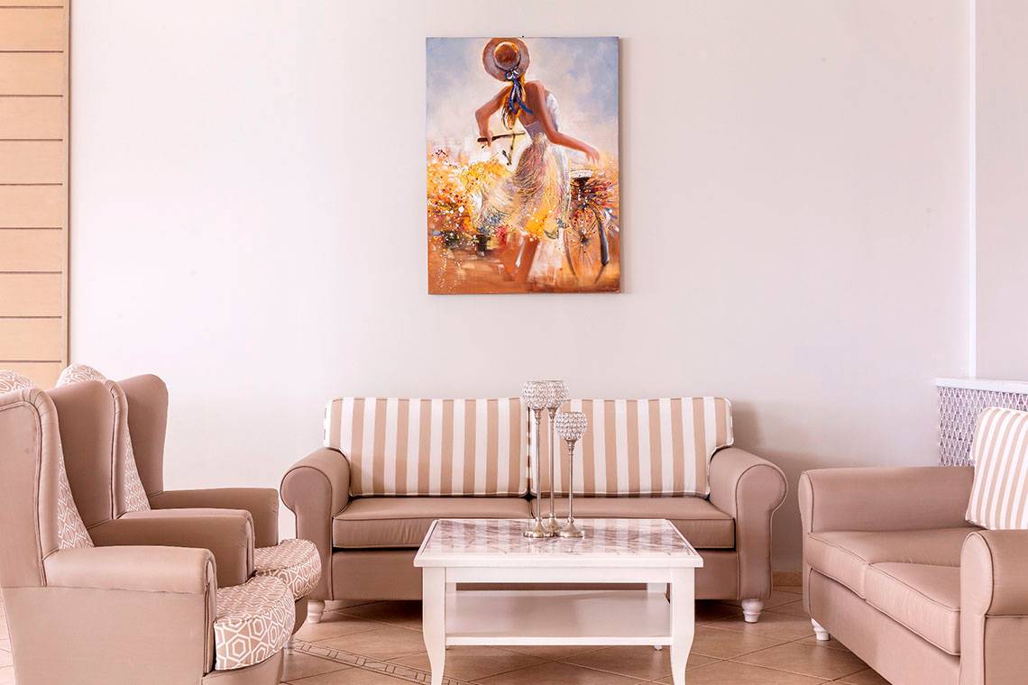 Wohnzimmer im Civitel Creta Beach Hotel mit Sofas, Stühlen und einer Wandmalerei.