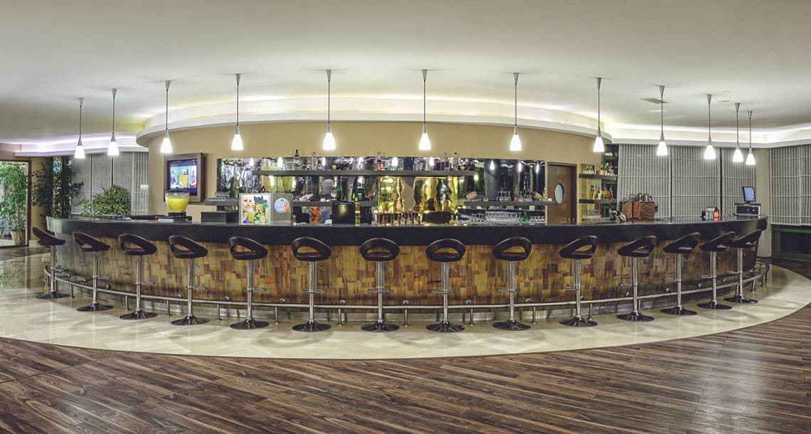Die elegante Bar im VONRESORT Golden Coast Hotel mit Holzstühlen und einer Theke.