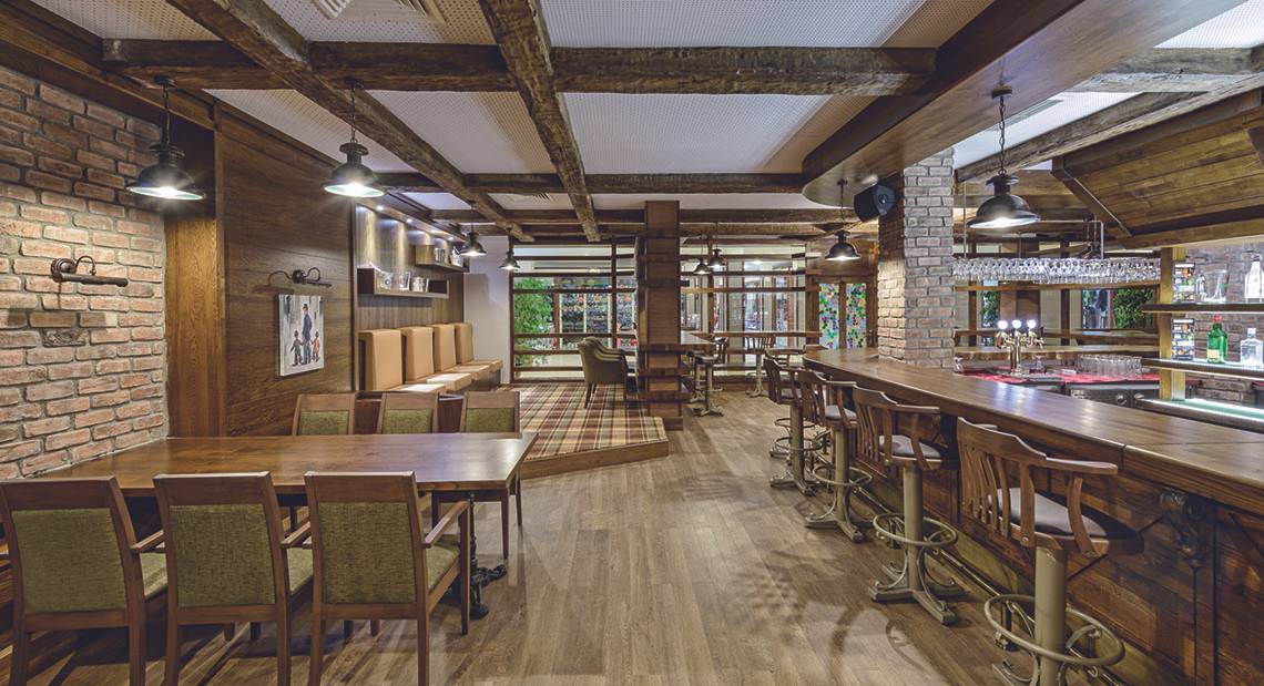 Innenansicht des Restaurants im VONRESORT Golden Coast mit Holzmöbeln, Ziegelwänden und einer Bar.