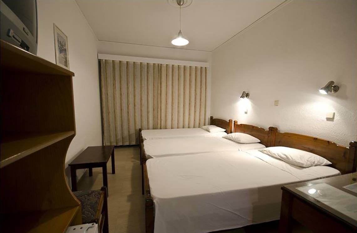 Drei Betten im Zimmer des Tropical Sol Hotels, alle mit weißen Laken bezogen.
