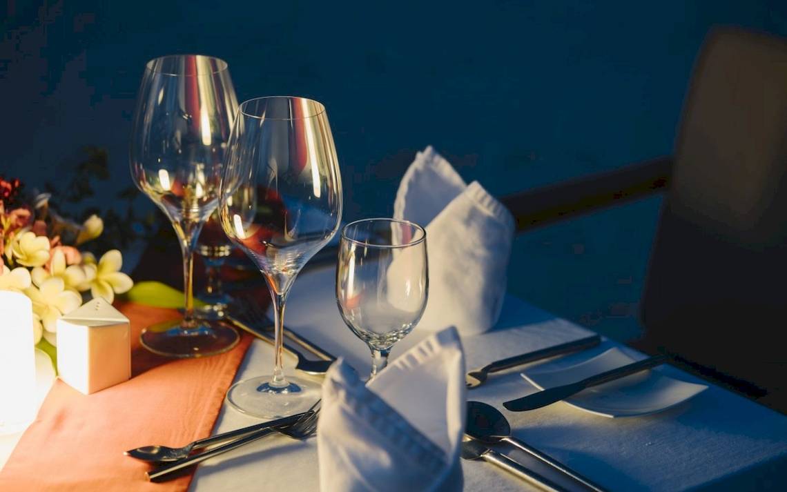 Tisch im Noku Maldives mit Gläsern, Besteck und Blumen dekoriert.
