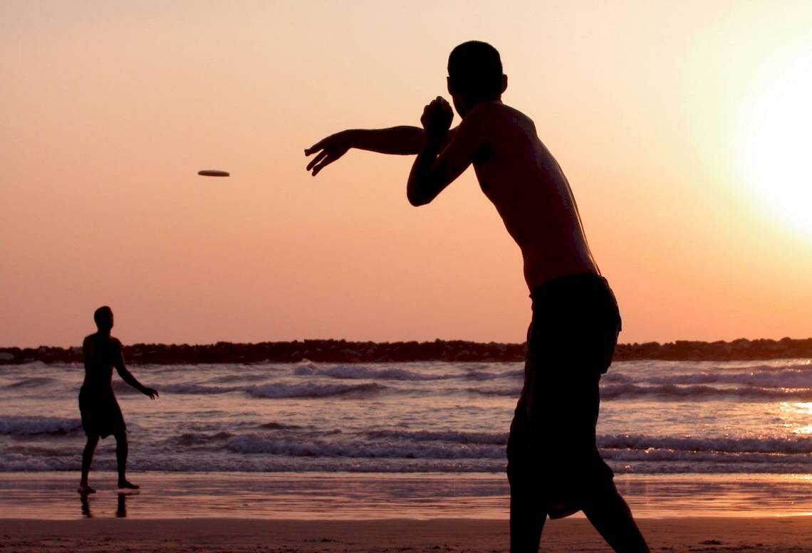 Silhouette von zwei Männern, die Frisbee am Strand spielen