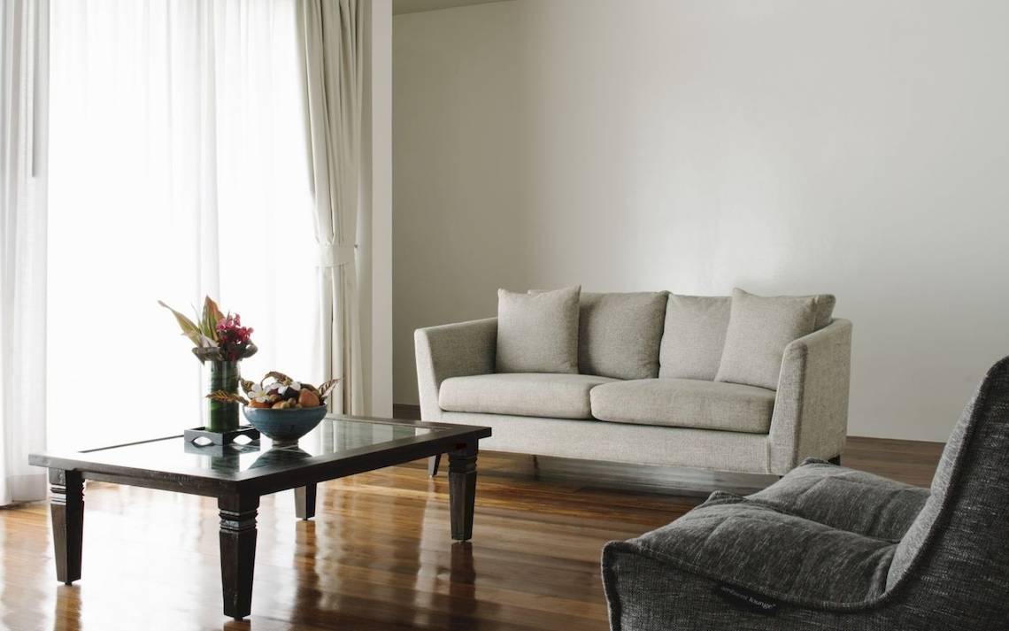 Wohnzimmer des Noku Maldives Hotels mit grauen Sofas, Tisch und Blumenvase.