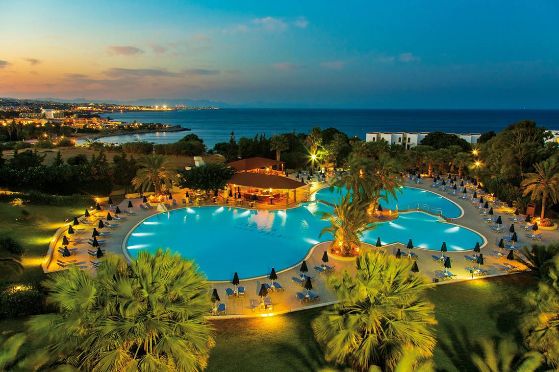Luftaufnahme des Poolbereichs des Kresten Palace Hotels mit zwei Schwimmbecken und vielen Liegestühlen.