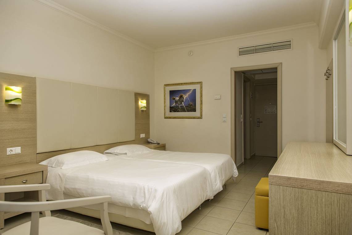 Doppelbettzimmer im Kresten Palace Hotel mit weißem Bettzeug, Nachttischen und einem Bild an der Wand.